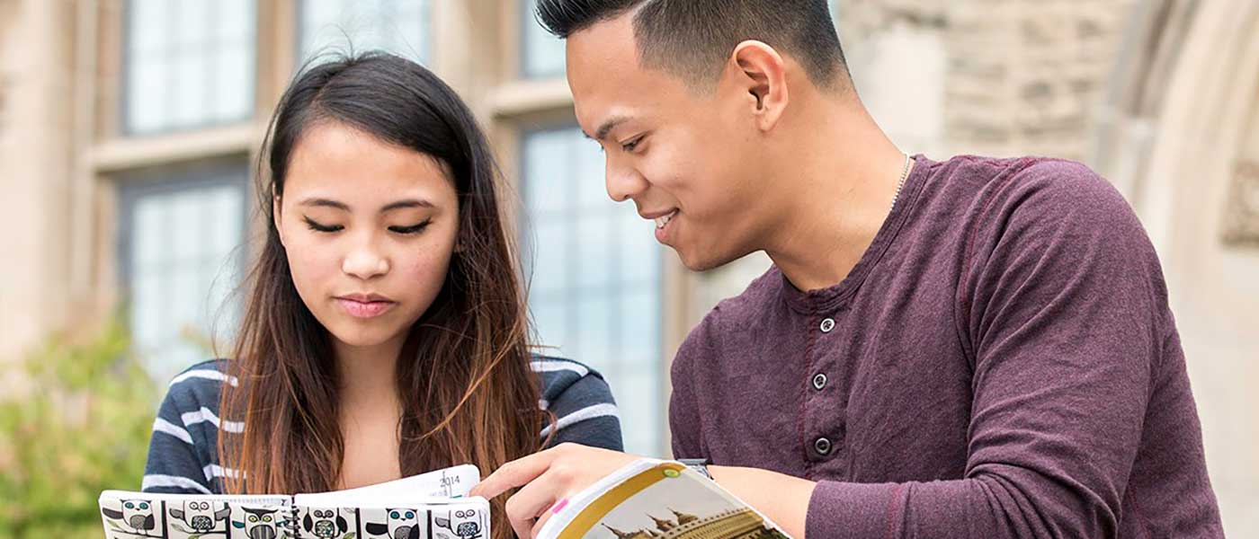 Two students looking at a planner and a textbook.